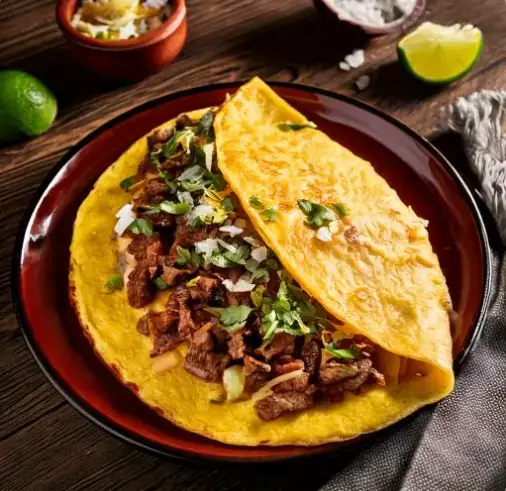 Carnitas breakfast with eggs, tortillas, and fresh toppings on a vibrant plate.