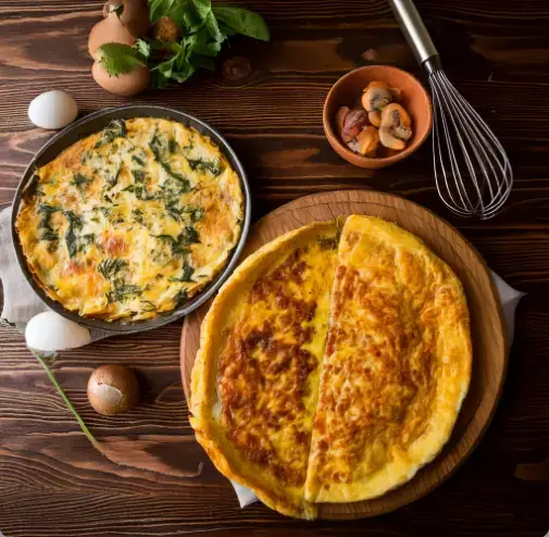 Comparison of a golden-brown frittata slice and a folded omelette on a plate with fresh herbs.