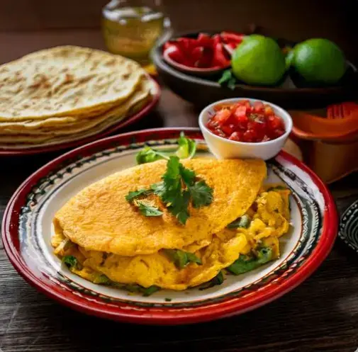 Mexican omelette with vibrant toppings like salsa, avocado, and fresh herbs on a plate.