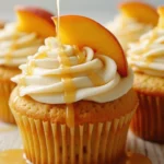 Honey Peach Cupcakes on rustic wooden table, with honey cream cheese frosting and fresh peach slices.