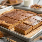 Close-up of gingerbread sheet pan pancake with whipped cream, maple syrup, and festive toppings like banana slices and pomegranate seeds